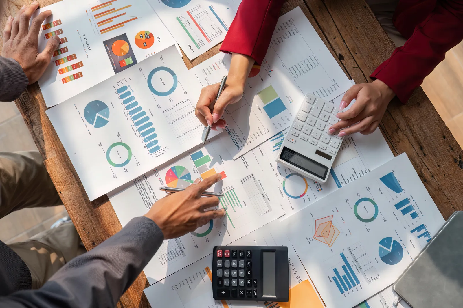 Mains analysant des graphiques financiers avec des calculatrices