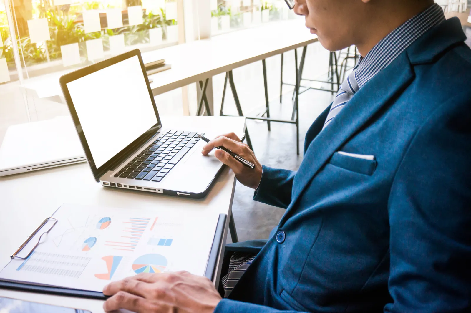 Homme travaillant sur ordinateur portable avec des graphiques imprimés