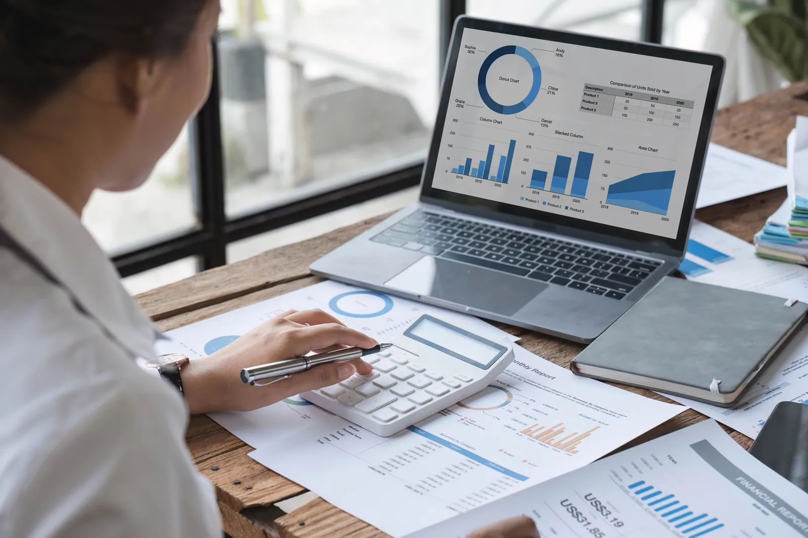 Femme calculant des montants devant un tableau de bord financier