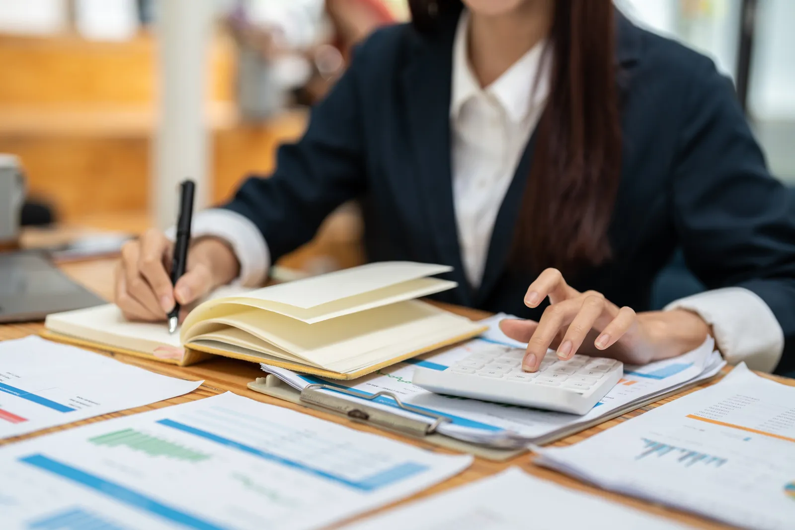 Femme calculant des montants avec une calculatrice et un carnet