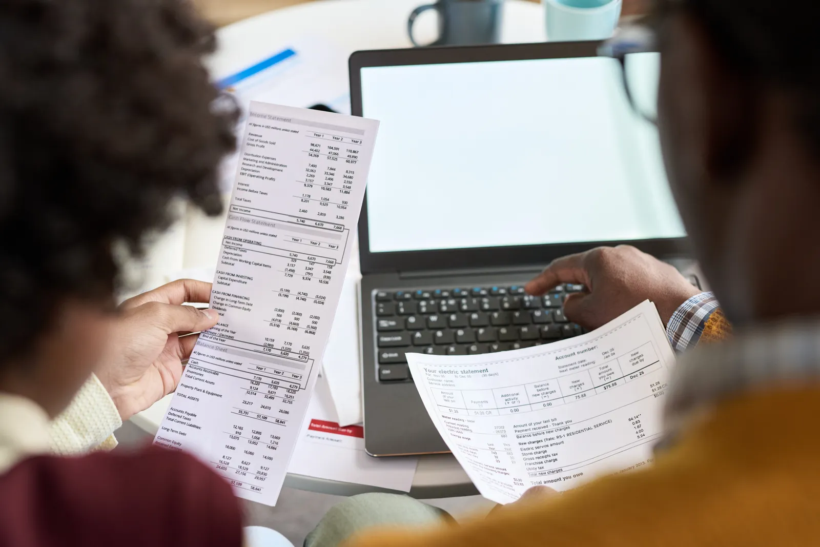 Deux personnes examinant des fiches de paie devant un ordinateur