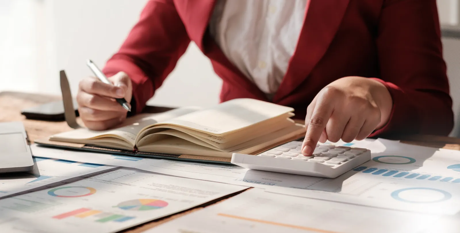 Femme calculant des montants avec une calculatrice et un carnet ouvert